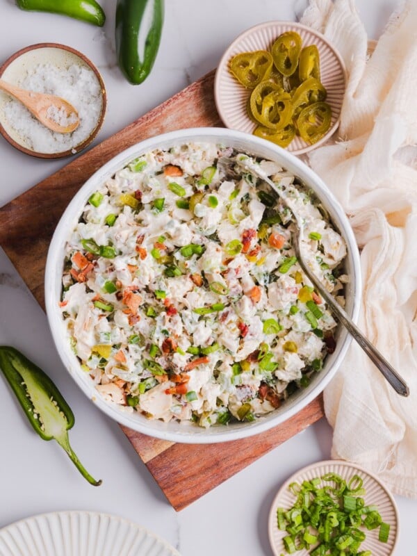 Overhead photo of jalapeno popper chicken salad in a white bowl, surrounded by other ingredients