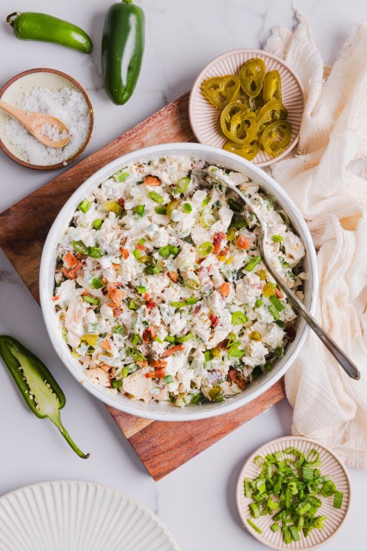 Overhead photo of jalapeno popper chicken salad in a white bowl, surrounded by other ingredients