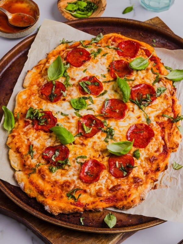 Overhead photo of Greek yogurt pizza crust topped with cheese, pepperoni, and basil