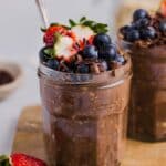 Chocolate protein overnight oats in glass jars, topped with fresh berries
