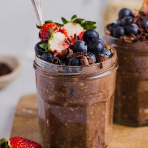 Chocolate protein overnight oats in glass jars, topped with fresh berries