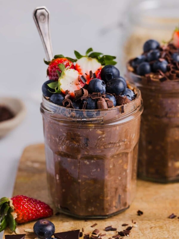 Chocolate protein overnight oats in glass jars, topped with fresh berries