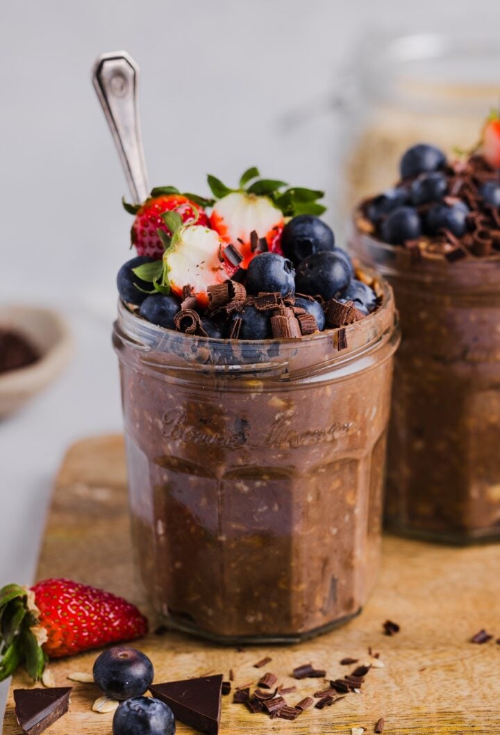 Chocolate protein overnight oats in glass jars, topped with fresh berries