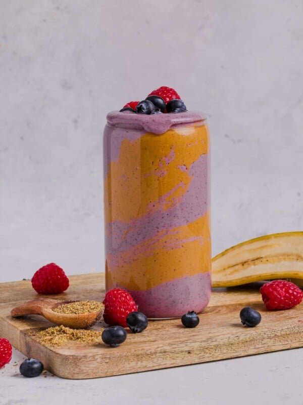 Peanut butter berry smoothie in a tall glass with peanut butter swirled in the glass