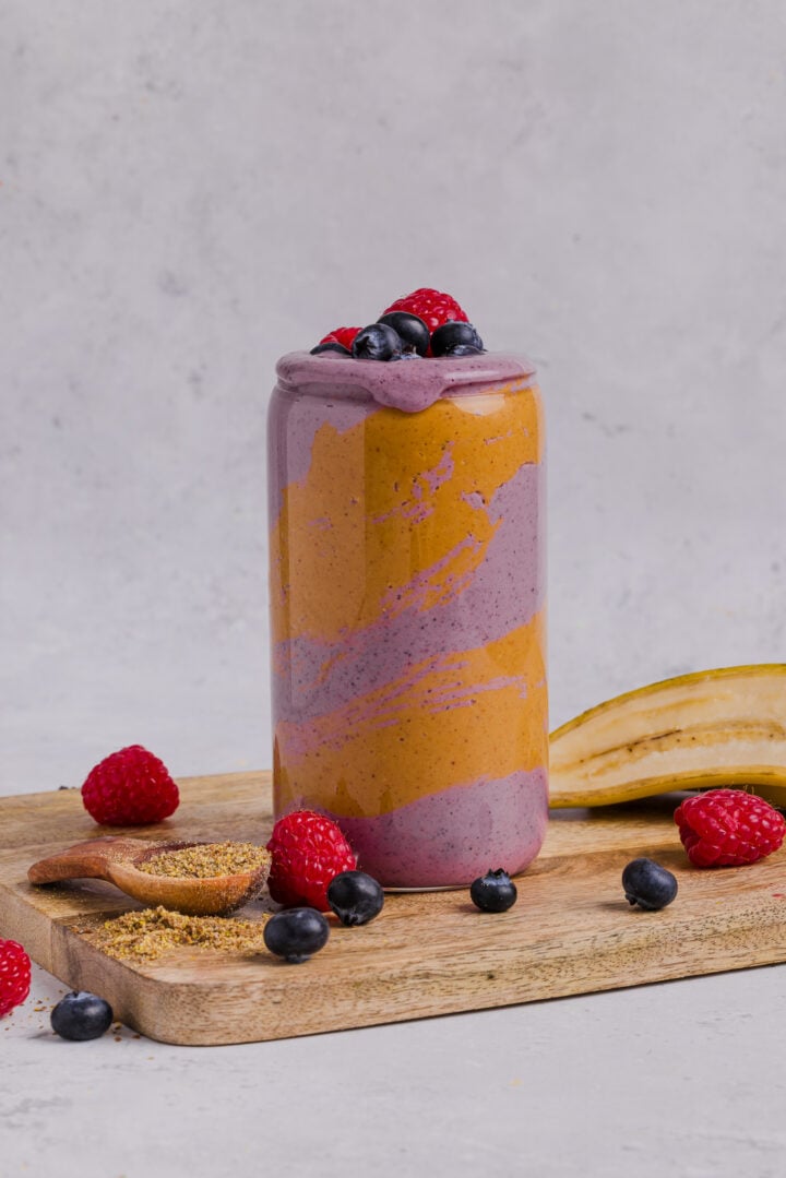 Peanut butter berry smoothie in a tall glass with peanut butter swirled in the glass