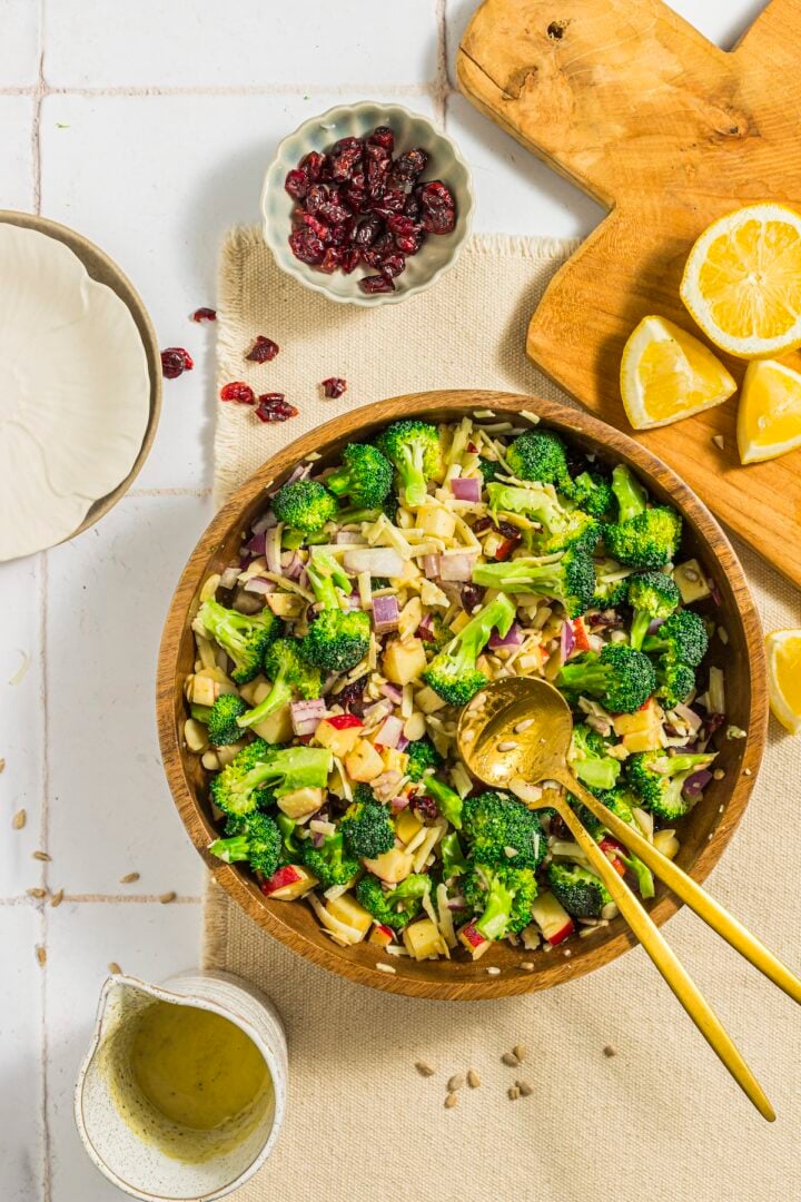 broccoli crunch salad in a large mixing bowl with lemons and craisins on the side.