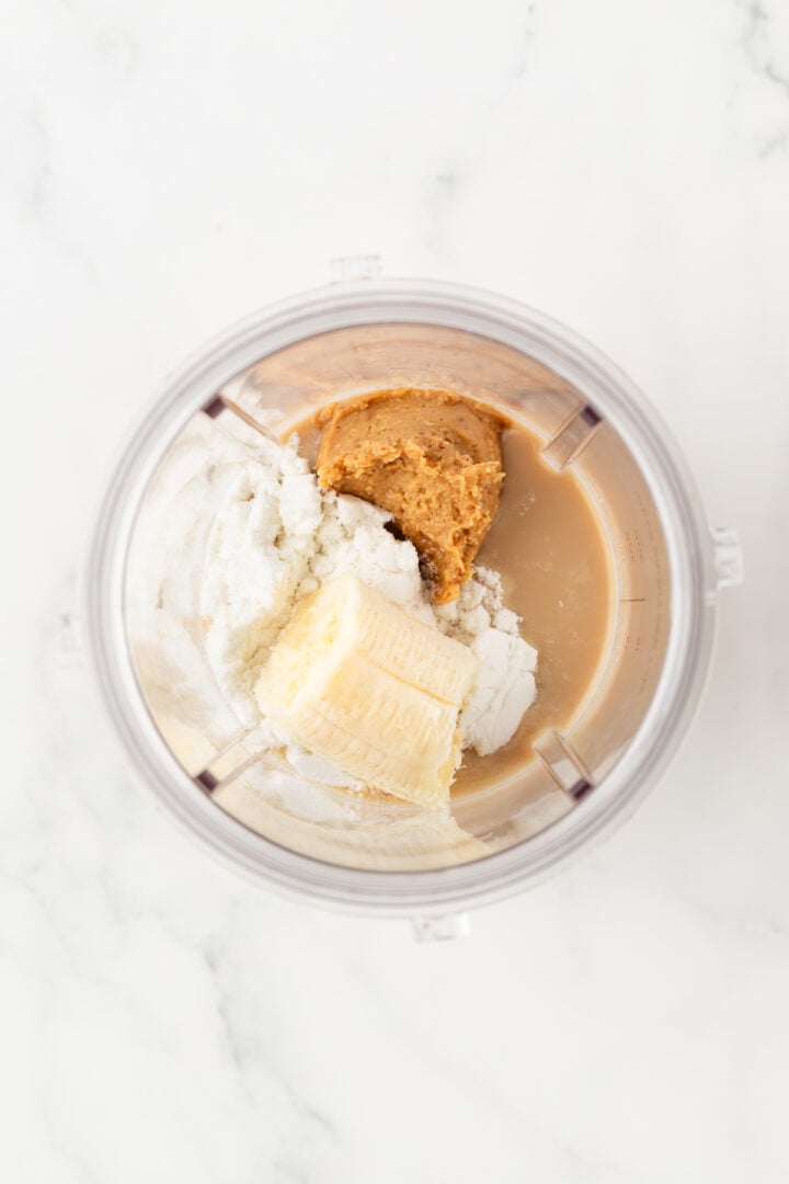 All ingredients for a coffee protein shake in a blender cup, unblended