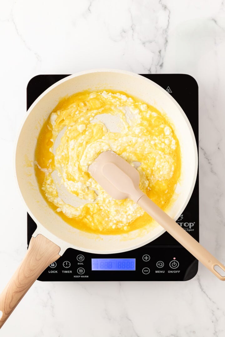 Eggs added to non-stick pan, and a spatula starting to scramble them.