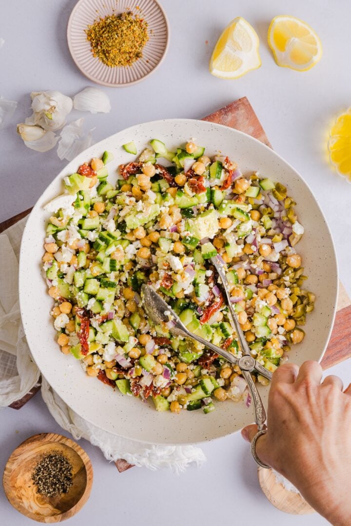 Chickpea cucumber feta salad being mixed in a large white bowl