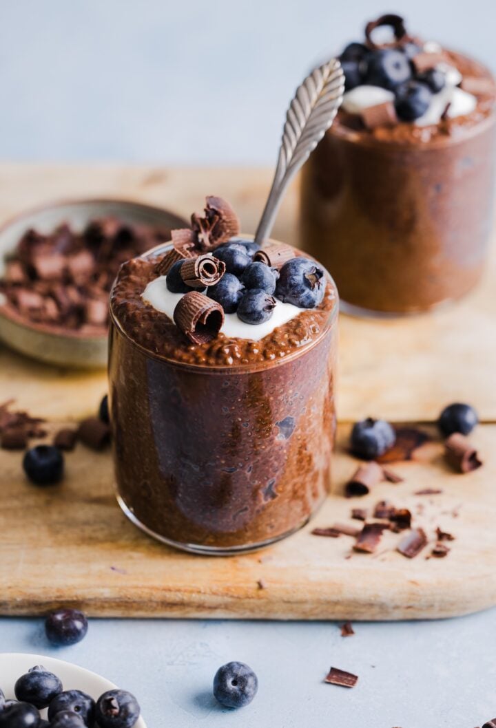 photo of chocolate chia pudding in a glass jar, topped with yogurt and fresh blueberries