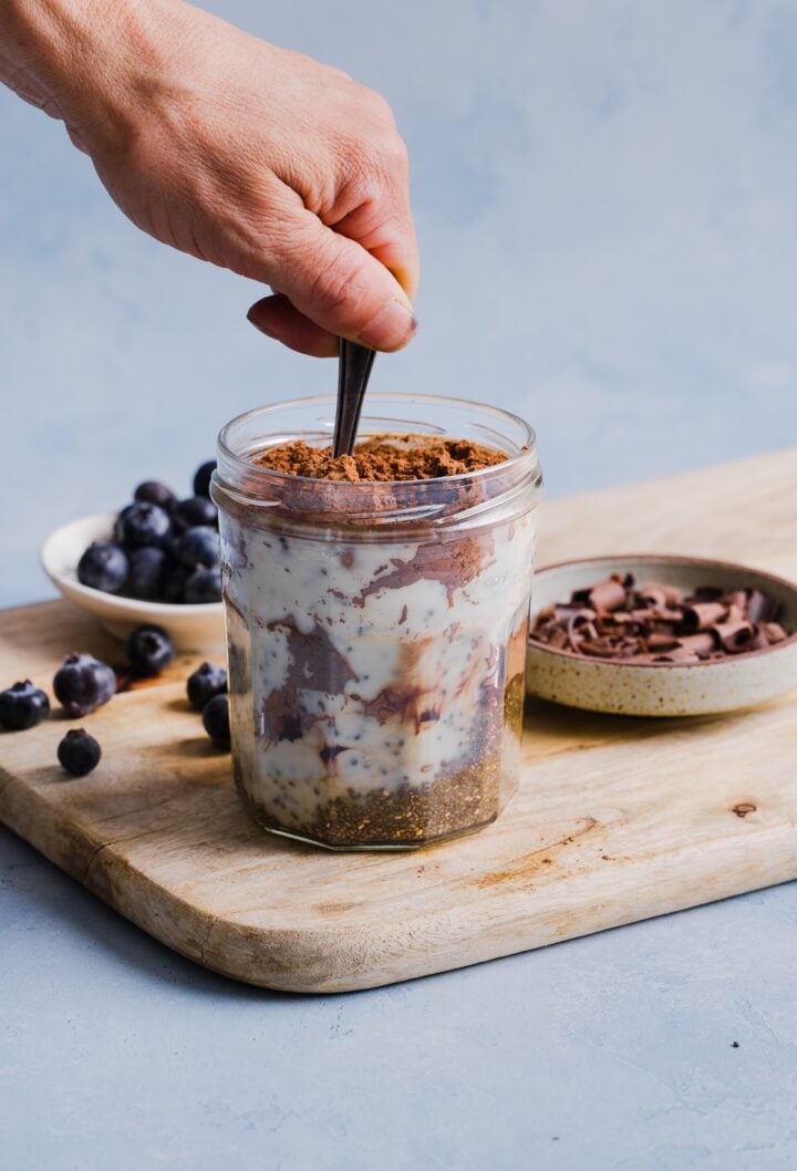 Chia pudding being stirred in a glass jar