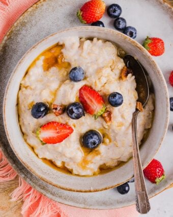 Overhead photo of egg white oatmeal in a bowl, with fresh berries and maple syrup