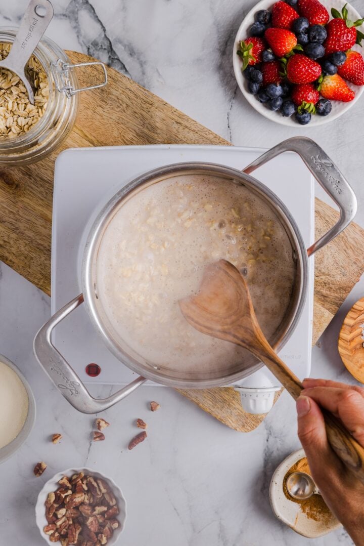 Protein oatmeal being stirred in a pot with a wooden spoon