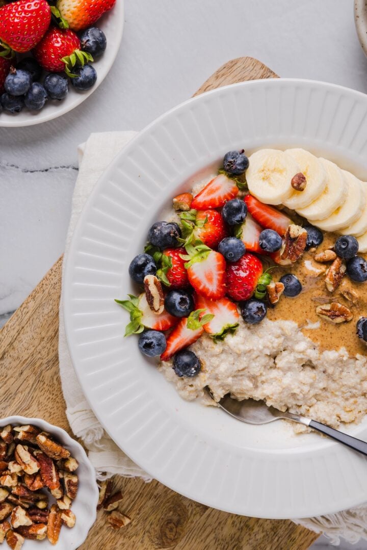 Close-up photo of protein oatmeal in a bowl with berries and nut butter for toppings
