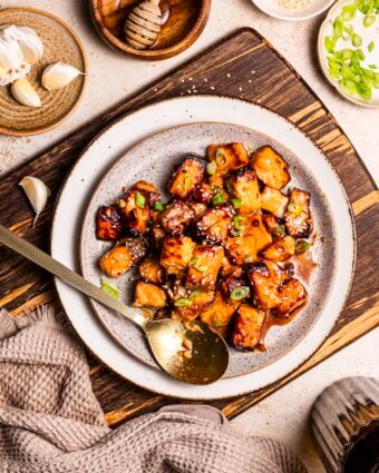 White bowl with air fryer salmon bites, topped with sliced green onion.