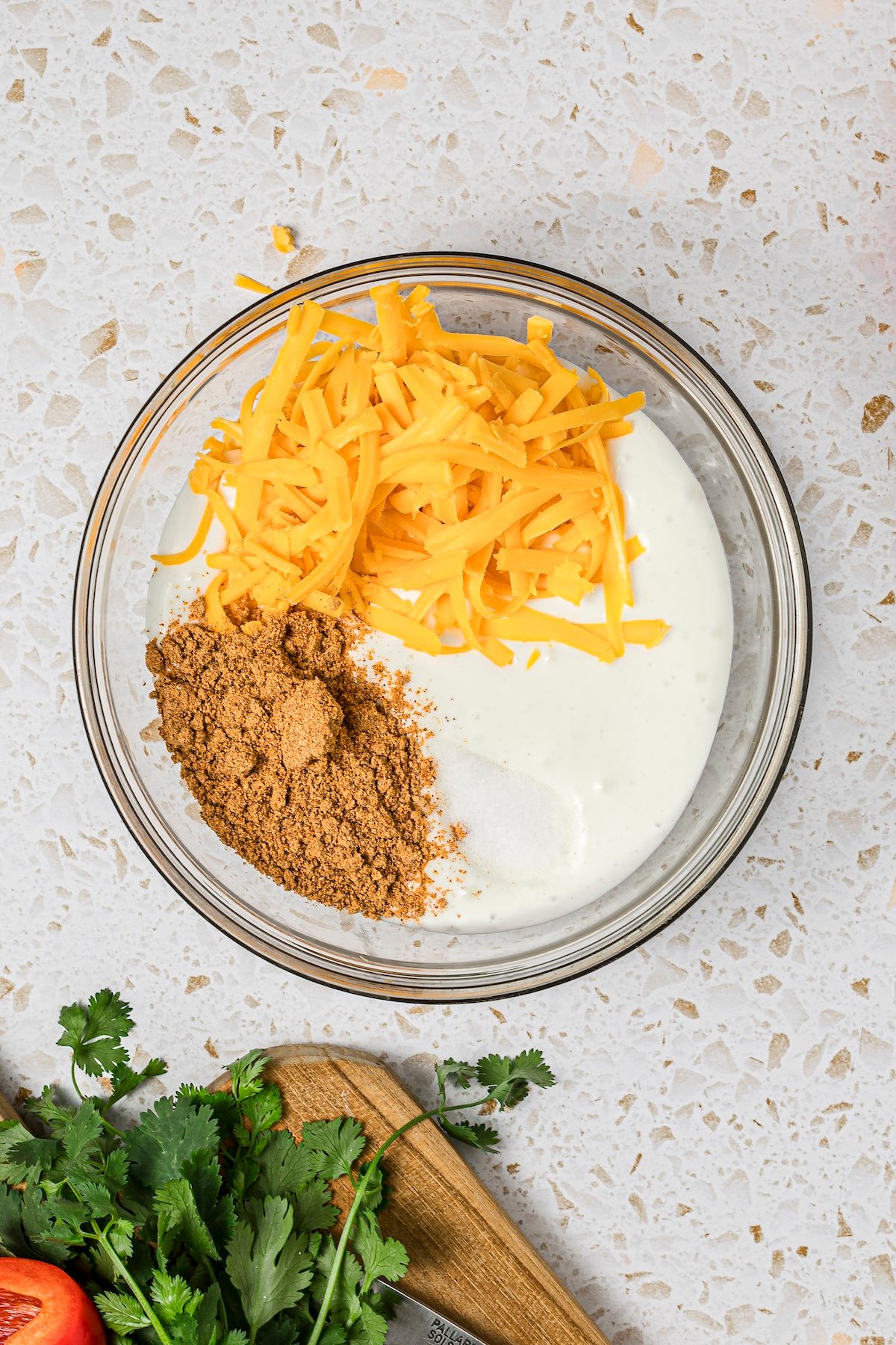 Blended cottage cheese with shredded cheddar and taco seasoning in a microwave-safe bowl.