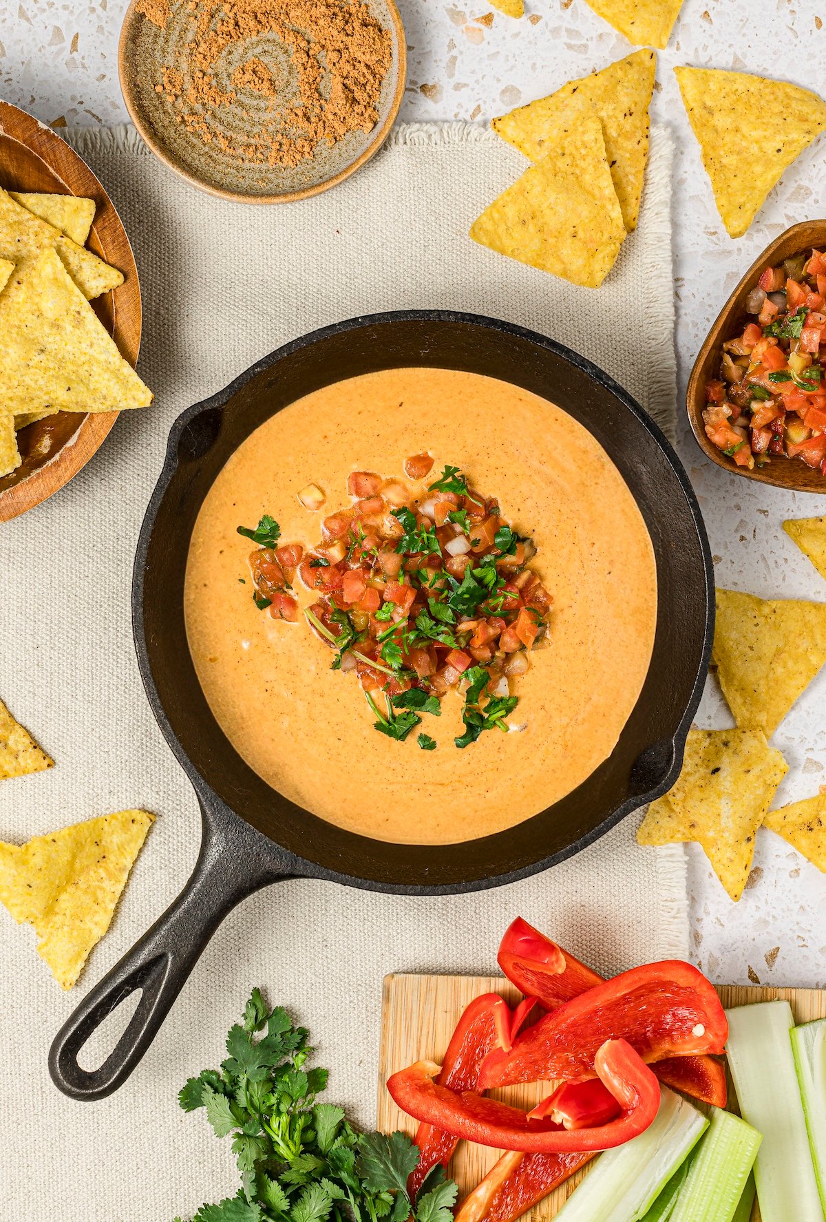 Cottage cheese queso in a small cast iron skillet, topped with pico de gallo and fresh cilantro.