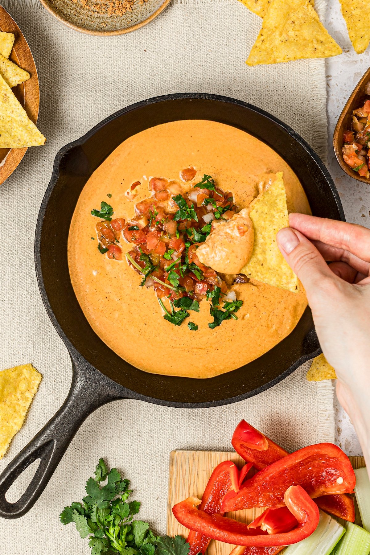 Viral high-protein cottage cheese queso dip with a woman's hands dipping into the dip with a tortilla chip.