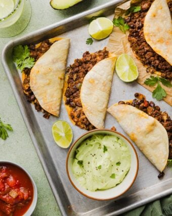 Crispy beef tacos with avocado lime crema on a sheet pan