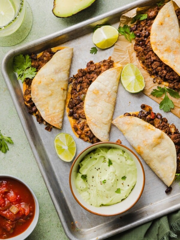Crispy beef tacos with avocado lime crema on a sheet pan