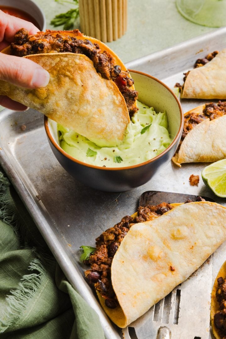 Crispy beef tacos dipped into avocado lime crema.