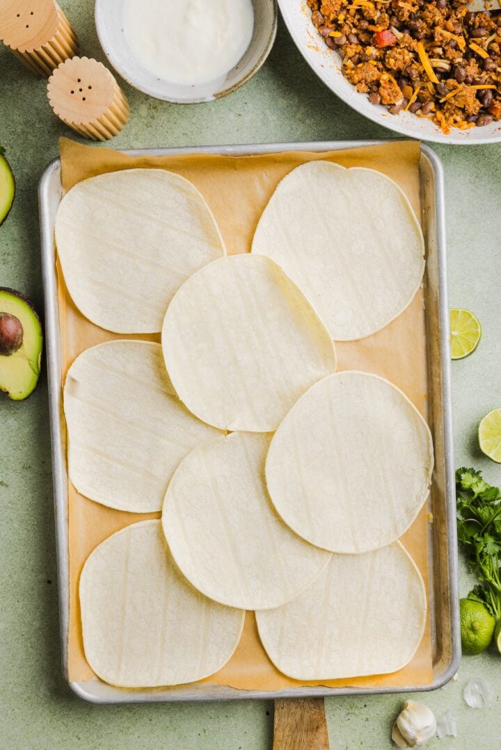 Tortillas warmed on a parchment-lined sheet pan.