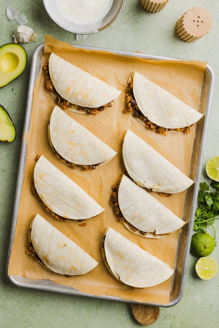 Baked crispy beef tacos prepared on a sheet pan, before baking.