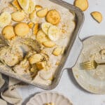 Dairy-free banana pudding in a baking dish, being scooped onto a serving plate.