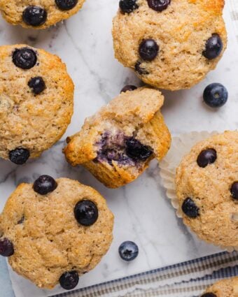 Whole wheat blueberry muffins on a grey marble counter top.