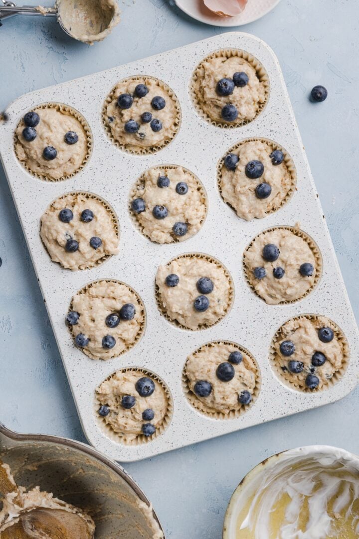 Whole wheat blueberry muffin batter in prepared muffin tin, before baking.