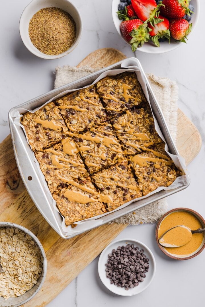 Peanut butter baked oatmeal in a baking pan, sliced and drizzled with extra peanut butter.