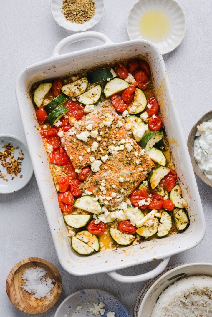 Baked greek salmon in a large white baking dish.