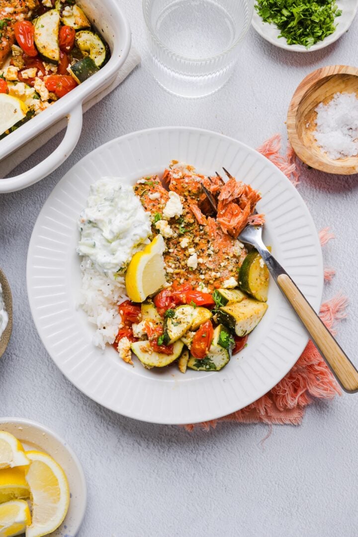 Baked greek salmon bowls with roasted vegetables and tzatziki.