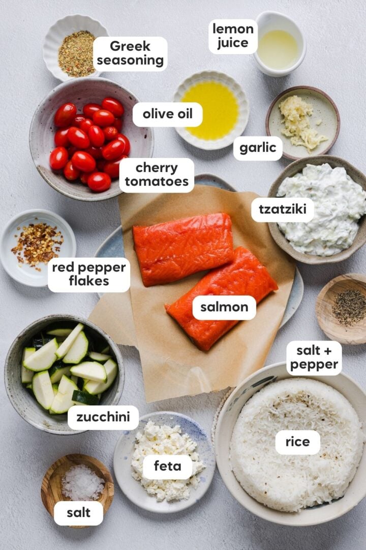 Labeled photo of ingredients for baked greek salmon bowls, displayed in bowls on a white counter top.