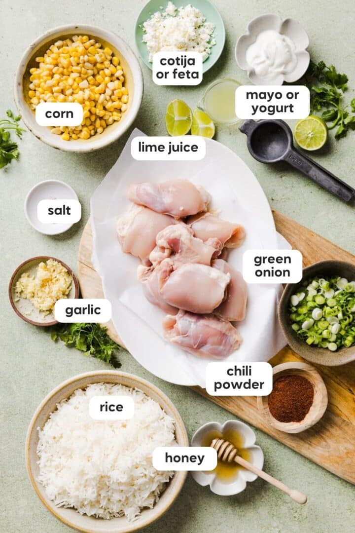 Ingredients for street corn chicken and rice bowl displayed in small bowls on a green marble counter.