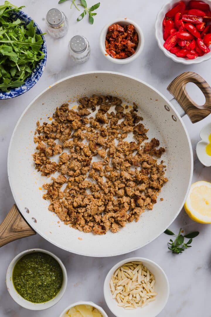 Italian sausage cooked and crumbled in a saute pan.