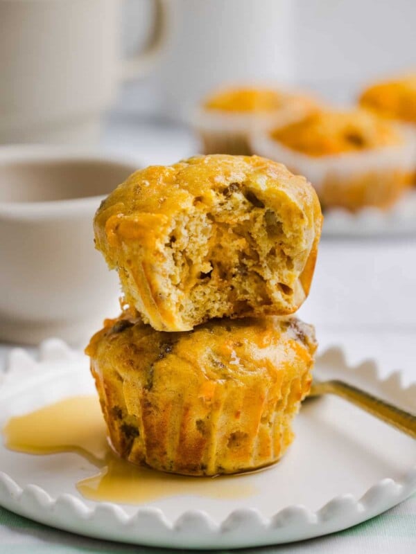 Two protein mcgriddle muffins stacked on a white plate with maple syrup.