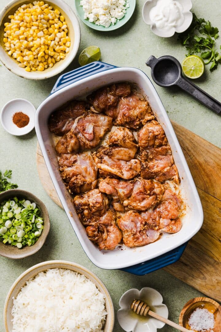 Raw chicken thighs in a baking dish with lime juice and seasonings.