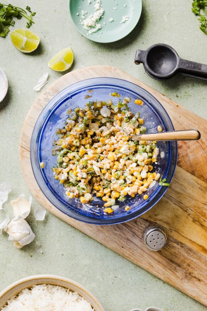 Street corn topping mixed in a blue mixing bowl with feta and mayonnaise.