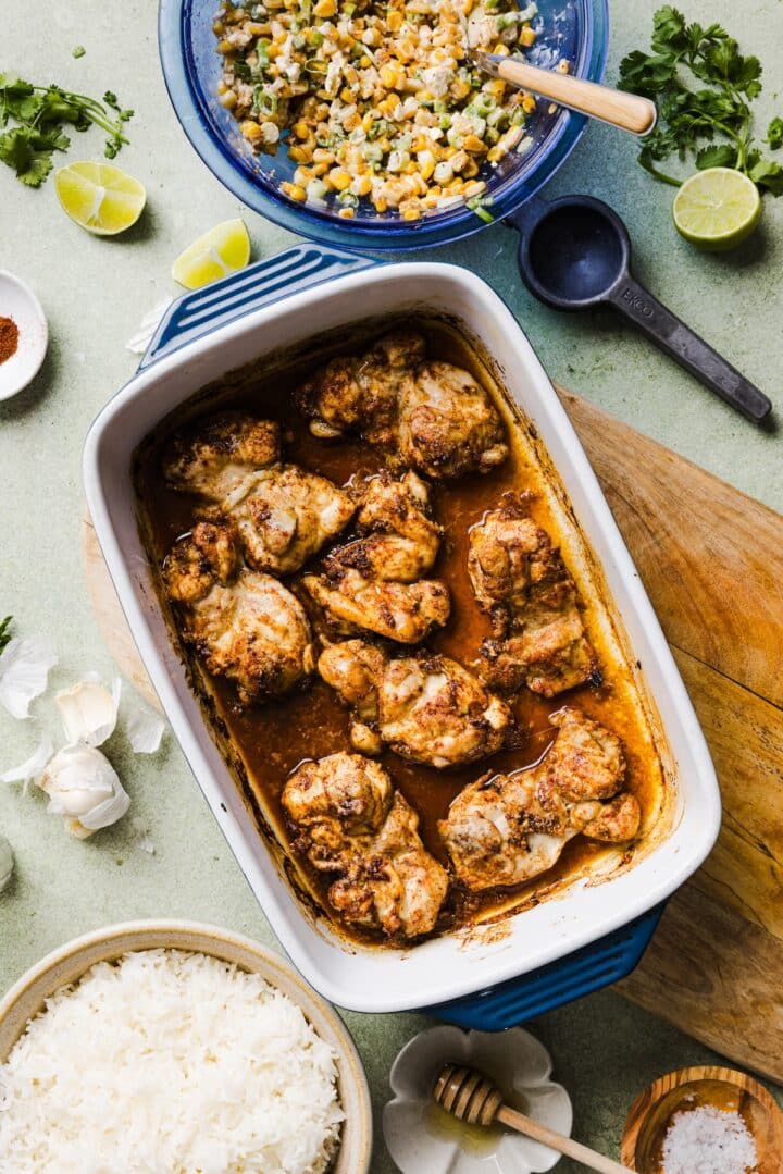 Cooked chicken thighs in a baking dish with lime juice and seasonings.