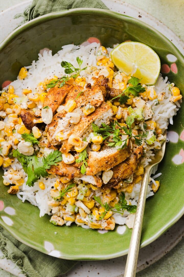 Street corn chicken and rice bowl garnished with cilantro and a lime wedge.