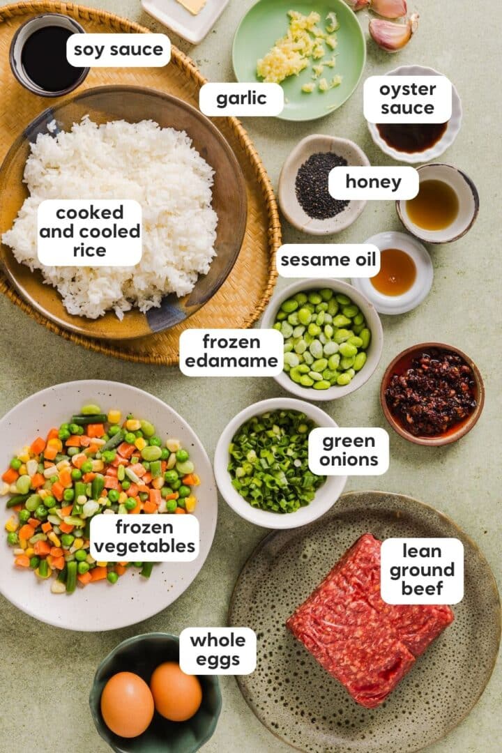 Labelled photo with ingredients for ground beef fried rice displayed in bowls on a green kitchen counter.