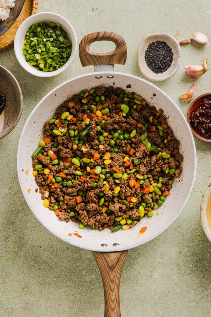 Ground beef cooked with vegetables in a pan.