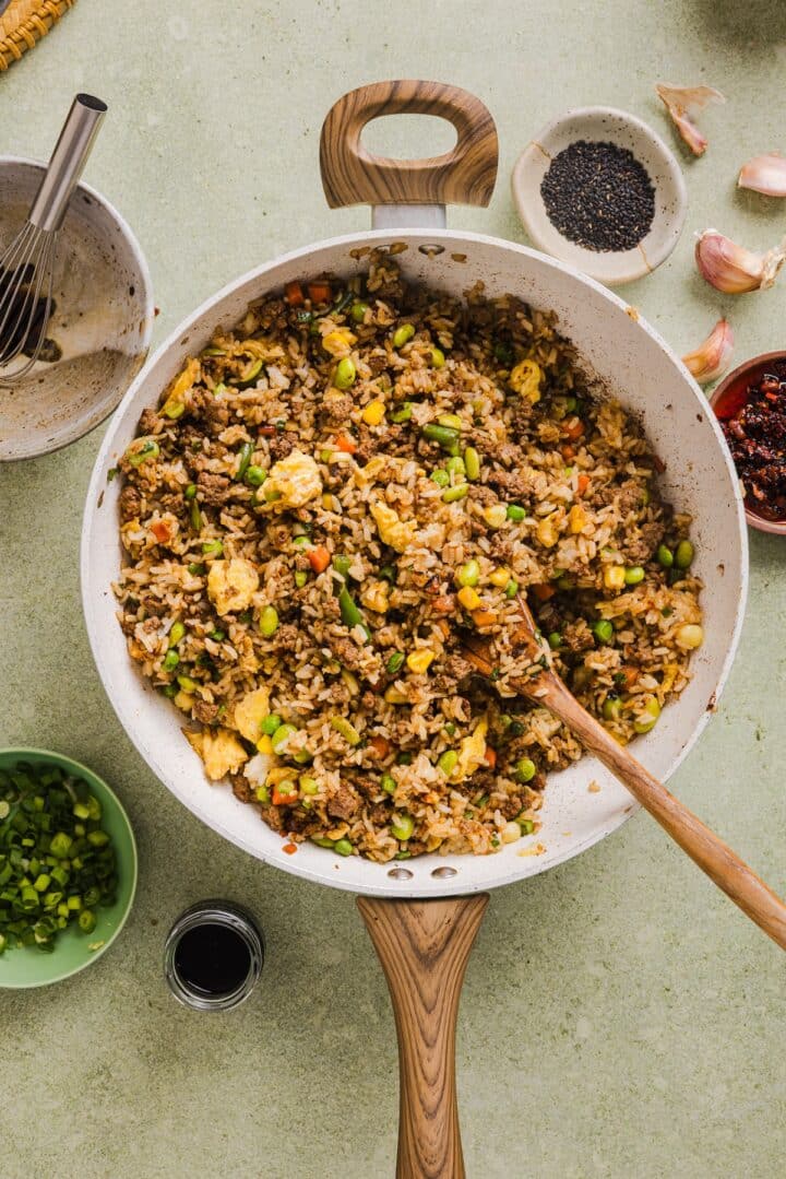 Beef fried rice in a large pan with a wooden spoon.