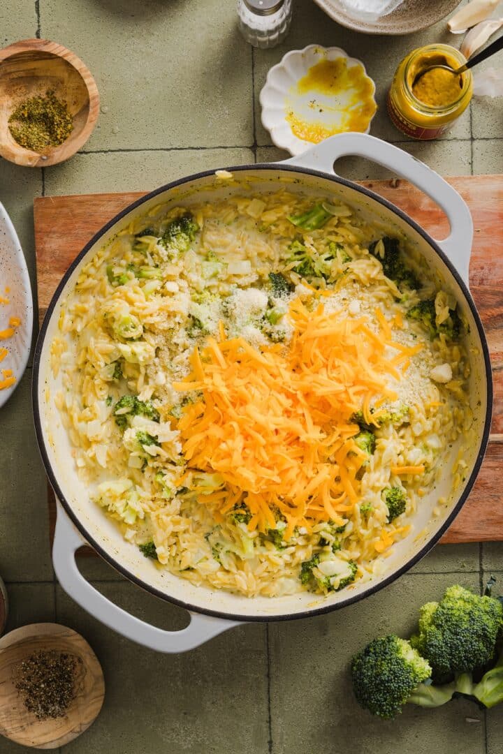 Shredded cheese added to broccoli cheddar orzo.