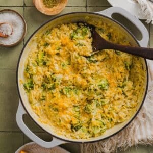 One-pot broccoli cheddar orzo in a braiser pan on a green tile counter.