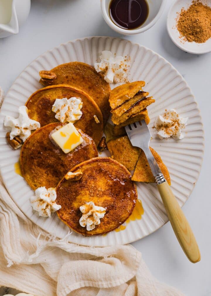 Pumpkin protein pancakes on a plate with maple syrup.