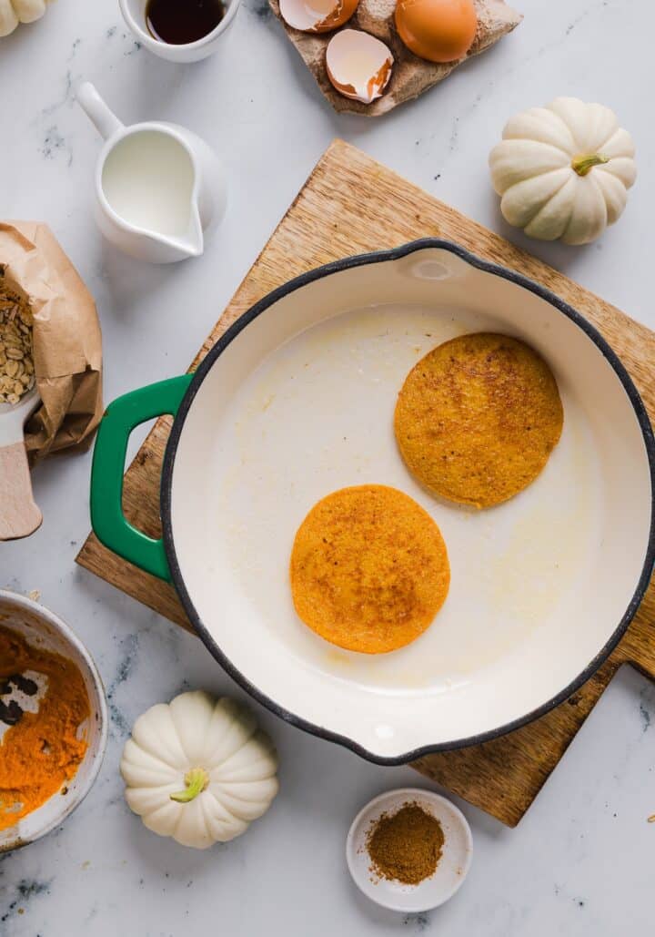 Pumpkin pancakes cooked on a white skillet.