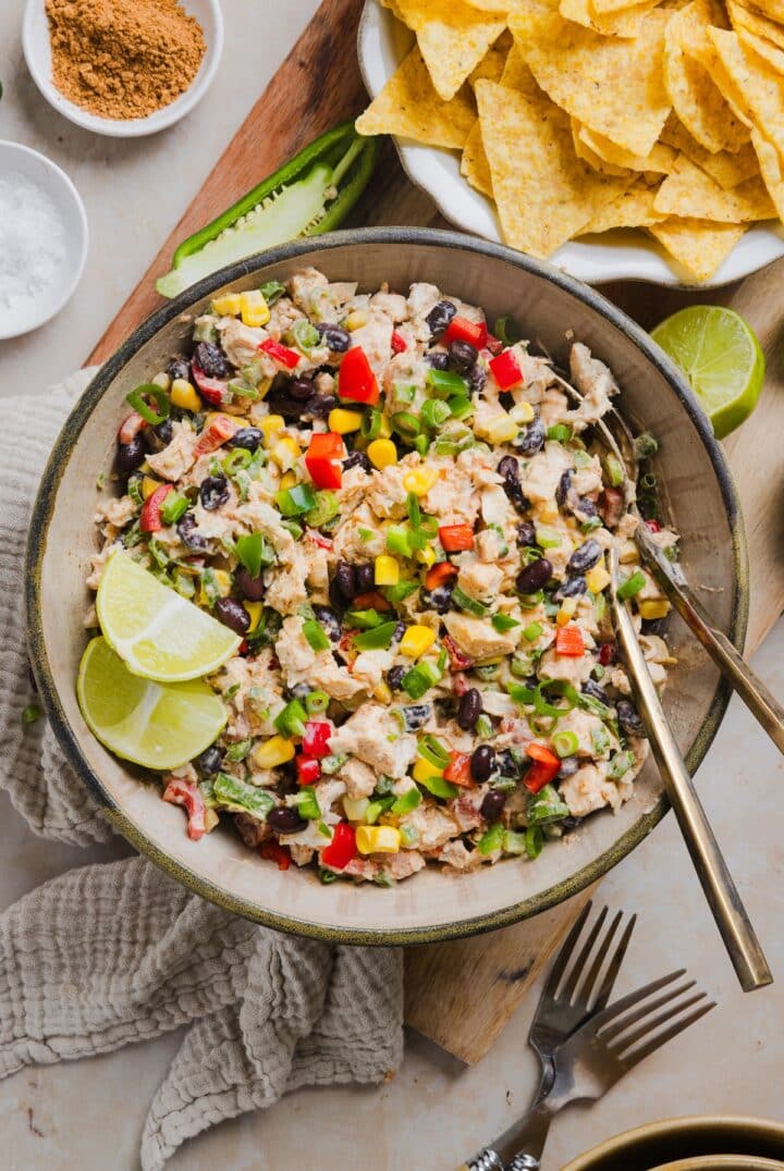 Southwest chicken salad in a serving bowl with lime wedges.