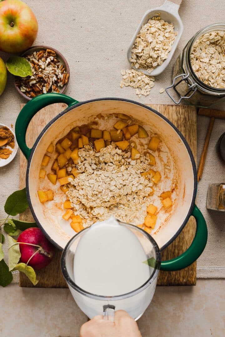 Milk being poured into a small pot to make apple cinnamon oatmeal.
